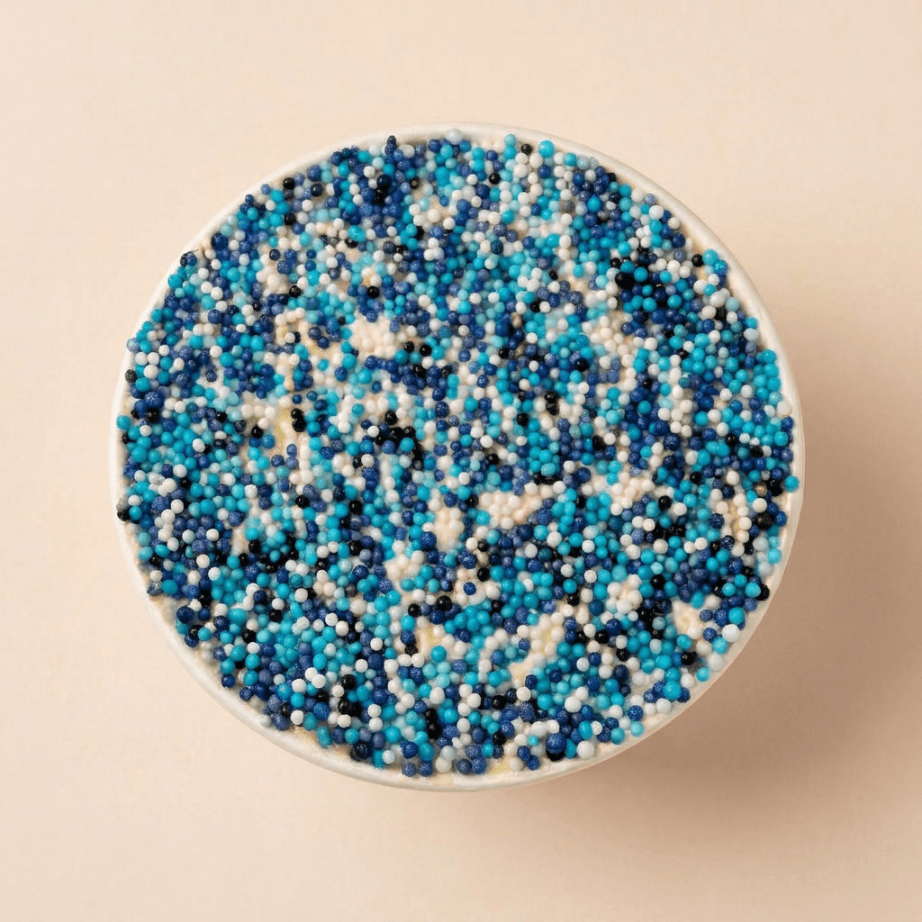 Bovenaanzicht van een bosbessen dotcake afgewerkt met roomkaasfrosting en een feestelijke mix van blauwe, witte en donkerblauwe suikerparels.