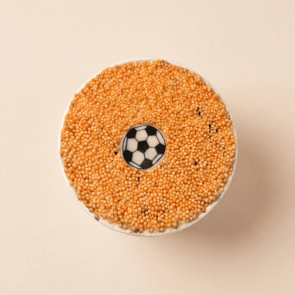 Aangesneden WK Special dotcake met zachte vanillecake en Oreo stukjes, afgewerkt met roomkaas frosting, oranje spikkels en een voetbaldecoratie.