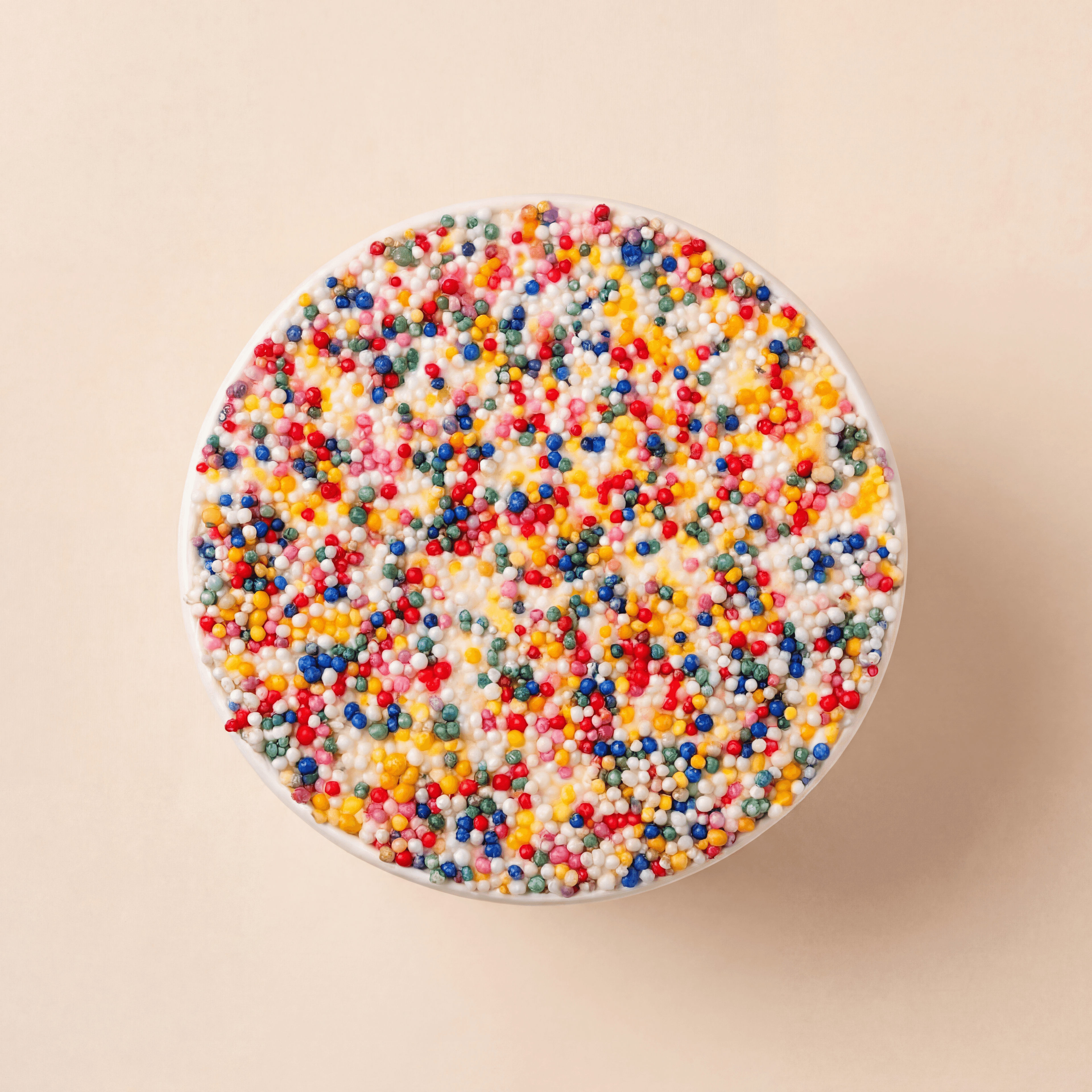 Bovenaanzicht van een vanille dotcake met romige roomkaasfrosting en een feestelijke disco dip van kleurrijke suikerparels.